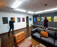 Homens observando obras da mostra Paisagens Distópicas
