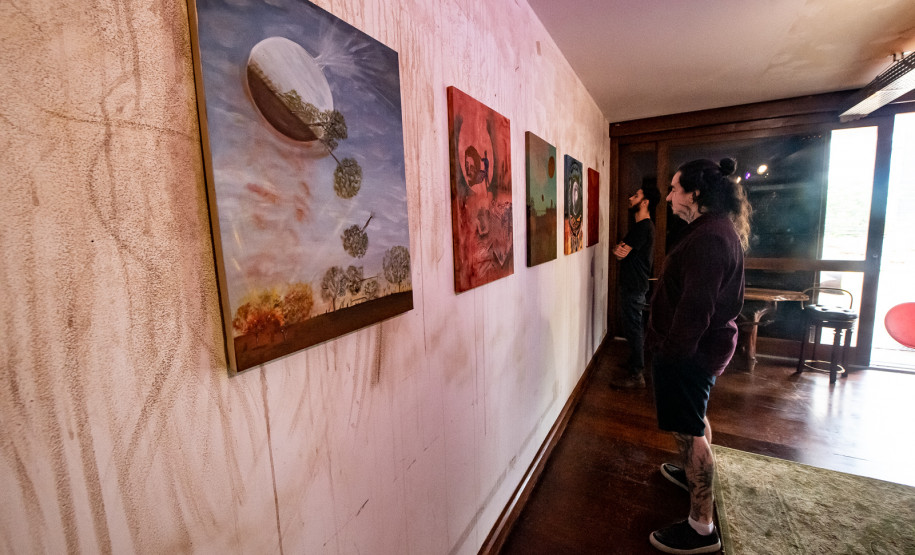 Homem observando obras da mostra Paisagens Distópicas