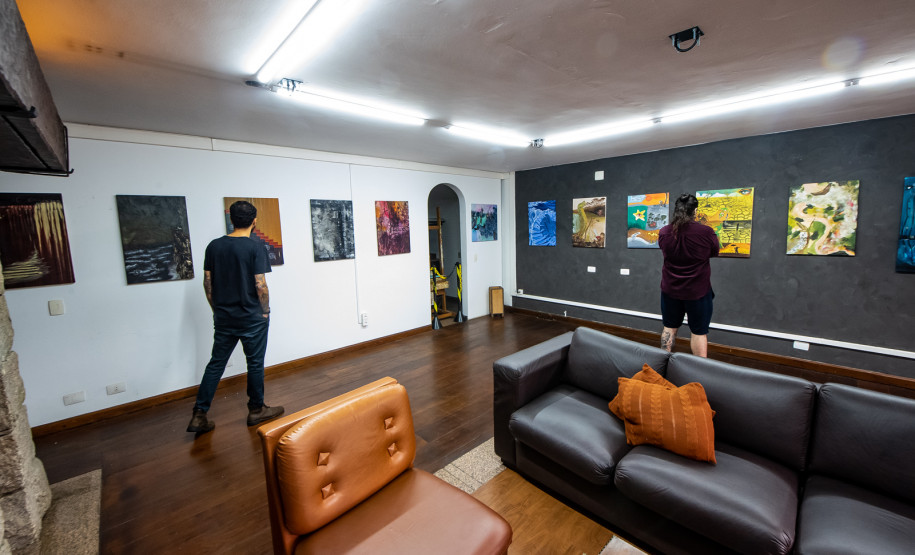 Homens observando obras da mostra Paisagens Distópicas