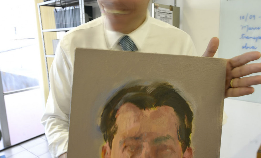 O chinês Tong Yanrunan.  trabalha com retratos "face a face". Na foto, o diretor do MCAA com obra pintada pelo artista.